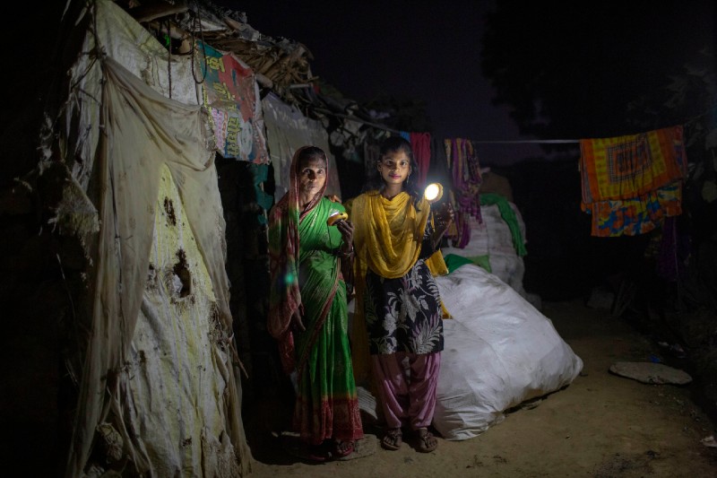 Two women with solar lights in India slum